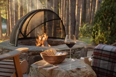 a glass of wine sitting on a table with a fire pit at The Chatwal Lodge (All-Inclusive) - in The Unbound Collection by Hyatt in White Lake