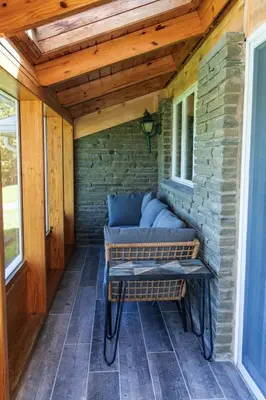 a porch with a bench and a brick wall at Stony Fork Inn in Wellsboro