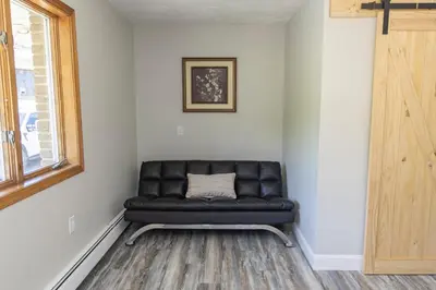 a black leather couch in a room with a window at Stony Fork Inn in Wellsboro