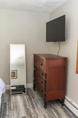 a bedroom with a dresser with a television and a mirror at Stony Fork Inn in Wellsboro