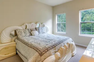 a bedroom with a large white bed with a wooden headboard at Centrally Located Family Home with Pool in Harleysville