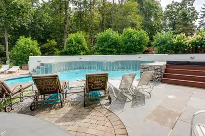a patio with chairs and a table next to a swimming pool at Centrally Located Family Home with Pool in Harleysville