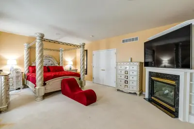 a bedroom with a red bed and a fireplace at Centrally Located Family Home with Pool in Harleysville