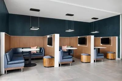 a waiting room with tables and chairs and televisions at Courtyard by Marriott New Castle in New Castle
