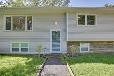 a white house with a blue door and windows at Kiamesha Lake Home with Deck 4 Mi to Resorts World! in Monticello