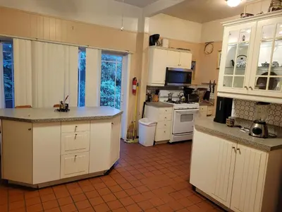 a kitchen with white cabinets and a red tile floor at A Victorian home in Philadelphia