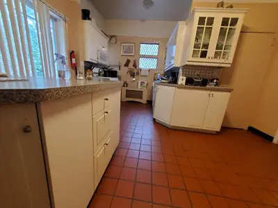 a kitchen with white cabinets and a red tile floor at A Victorian home in Philadelphia