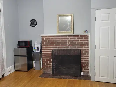 a living room with a brick fireplace and a microwave at A Victorian home in Philadelphia