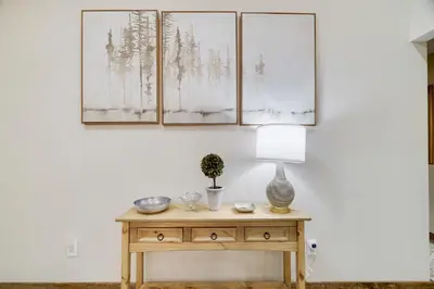 a room with a table with a lamp and paintings on the wall at Whiskey Pines Retreat! Single Level Home, Outdoor Firepit, AC, BBQ! Sleeps 9 in Lake Harmony! in Lake Harmony