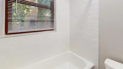 a white bathroom with a tub and a window at Lennox C101 Perfect & Peaceful Studio Apt in Philadelphia
