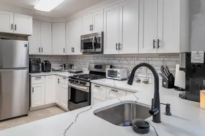 a kitchen with white cabinets and a stainless steel sink at 3br private Apartment in Jersey City