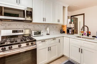 a kitchen with white cabinets and a stove top oven at 3br private Apartment in Jersey City