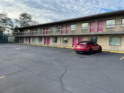 a red car parked in a parking lot in front of a building at Express Inn-Rahway in Rahway