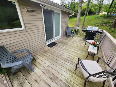 a wooden deck with chairs and a grill on a house at little cozy house in a village in Mountain Dale