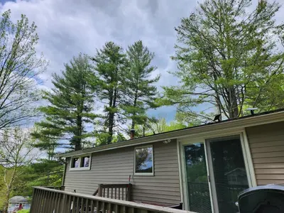 a house with a porch and trees in the background at little cozy house in a village in Mountain Dale