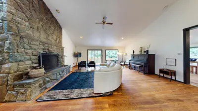 a living room with a large stone fireplace at The Stone Mason - Large Modern Home on 5 Acres - 2 Hrs from NYC in Pond Eddy