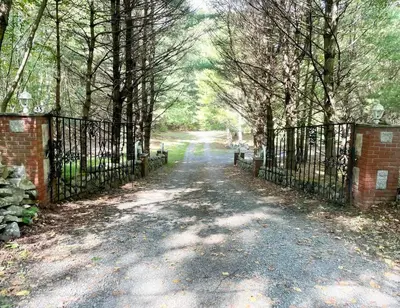 a driveway with a iron fence and trees at The Stone Mason - Large Modern Home on 5 Acres - 2 Hrs from NYC in Pond Eddy