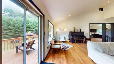 a living room with a large window and a piano at The Stone Mason - Large Modern Home on 5 Acres - 2 Hrs from NYC in Pond Eddy