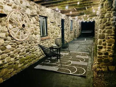 a room with a stone wall with a chair and a table at The Stone Mason - Large Modern Home on 5 Acres - 2 Hrs from NYC in Pond Eddy