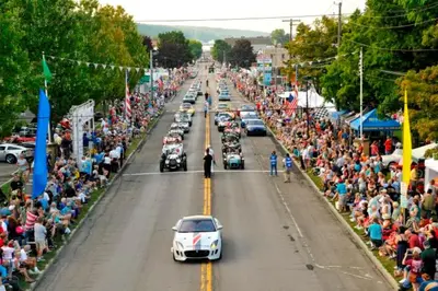 a group of cars driving down a street in a parade at Americas Best Value Inn Horseheads in Elmira