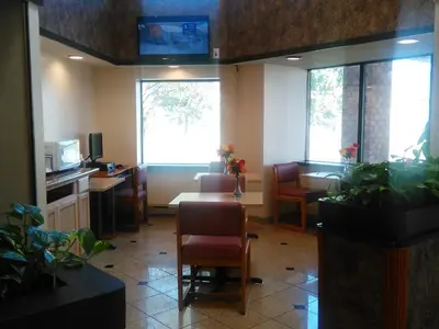 a waiting room with a table and chairs and windows at Americas Best Value Inn Horseheads in Elmira