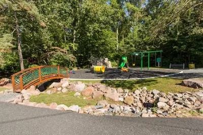 a park with a playground with a bridge and rocks at Sun Retreats Lancaster County in Narvon