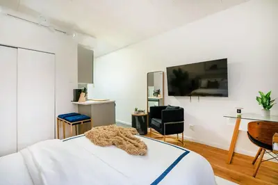 a bedroom with a white bed and a large tv at 74-1C New Studio With private outdoors - GYM in New York