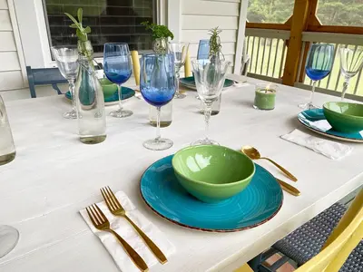 a table with a green bowl and plates and wine glasses at French Woods Farmhouse Bed & Breakfast in Hancock