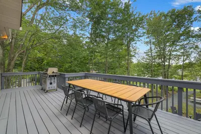 a wooden table and chairs on a deck at The Oasis at Arrowhead in Arrowhead Lake