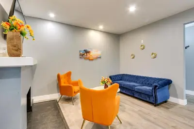 a living room with a blue couch and orange chairs at Chic Newark Vacation Rental 3 Mi to Airport! in Newark