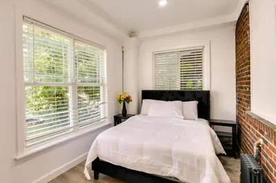 a white bedroom with a bed and two windows at Chic Newark Vacation Rental 3 Mi to Airport! in Newark