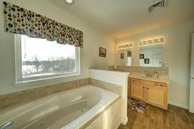 a bathroom with a tub and a sink and a window at Stunning Lakefront Home - Swim, Fish, Kayak, HotTub in Long Pond