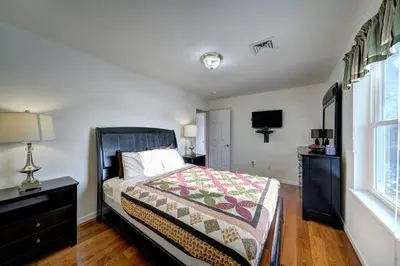 a bedroom with a bed and a dresser and a window at Stunning Lakefront Home - Swim, Fish, Kayak, HotTub in Long Pond