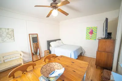 a room with a table and a bed and a ceiling fan at Cozy apartment in beautiful midtown Hoboken in Hoboken