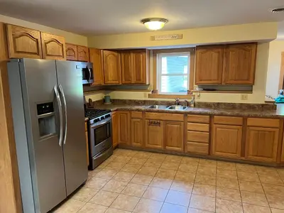 a kitchen with wooden cabinets and a stainless steel refrigerator at Wellsboro Rail Trail 1 in Wellsboro