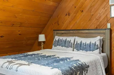 a bed in a room with a wooden ceiling at Rustic Luxury in the Pocono Mountains - Stag Lodge in Pocono Lake