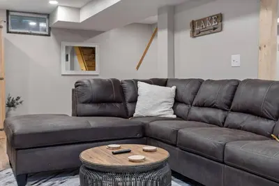 a living room with a brown leather couch and a table at Rustic Luxury in the Pocono Mountains - Stag Lodge in Pocono Lake