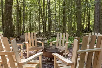 a group of chairs around a campfire in the woods at Rustic Luxury in the Pocono Mountains - Stag Lodge in Pocono Lake