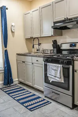 a kitchen with a stainless steel stove and white cabinets at Chic 4BR Dwelling with Backyard in Philadelphia in Philadelphia
