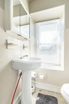 a white bathroom with a sink and a window at Chic 4BR Dwelling with Backyard in Philadelphia in Philadelphia