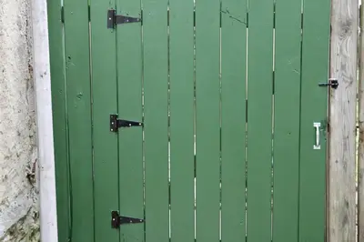 a green door with black hinges next to a wall at Chic 4BR Dwelling with Backyard in Philadelphia in Philadelphia