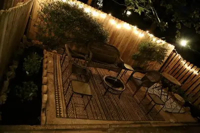 a garden with two chairs and a fence at night at Chic 4BR Dwelling with Backyard in Philadelphia in Philadelphia