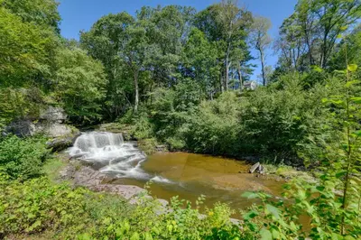 a creek with a waterfall in the middle of a forest at Rustic Bainbridge Retreat with Spacious Yard! in Bainbridge