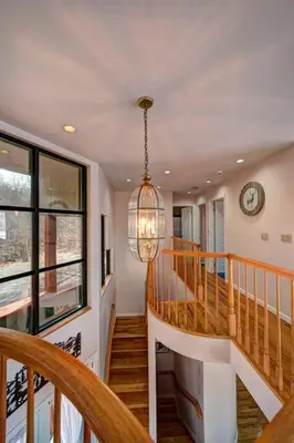 a hallway with a staircase with a clock and a chandelier at Magical Waterfront with 4-Season fun in Ski Resort in Lackawaxen