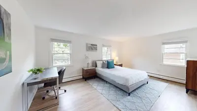 a bedroom with a bed and a desk and windows at pb 824 Furnished 2br Pool Gym Parking pb in Newark