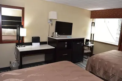 a hotel room with a bed and a desk with a television at Quality Inn East Stroudsburg - Poconos in East Stroudsburg