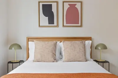 a bedroom with a bed with two lamps and two pictures on the wall at UWS 2BR w Elevator Gym DM Playroom Rooftop NYC-868 in New York
