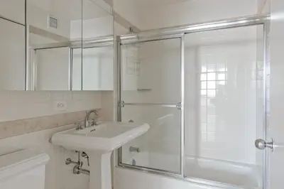 a white bathroom with a sink and a shower at UWS 2BR w Elevator Gym DM Playroom Rooftop NYC-868 in New York