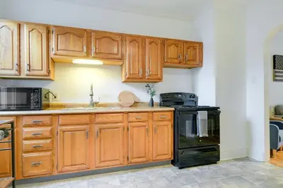 a kitchen with wooden cabinets and a black stove at Cozy Retreat in Downtown Lancaster with Backyard Patio in Lancaster