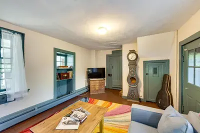 a living room with a table and a clock at Jim Croces Farmhouse Apartment in Downingtown! in Downingtown